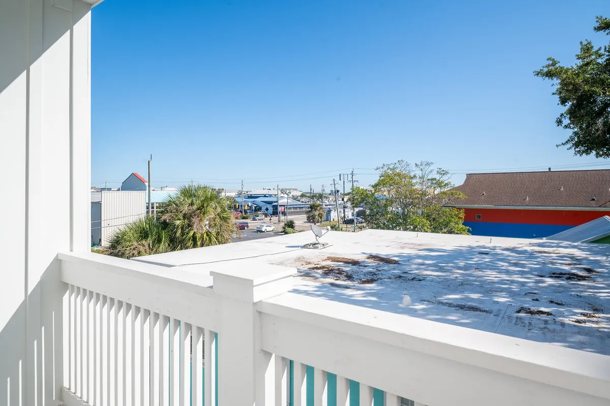 This image features palm trees swaying under a blue sky, with commercial buildings suggesting a lively beachside town atmosphere. The scene invites the viewer to imagine strolling to local restaurants and shops, perfectly aligning with the idea of being steps from Carolina Beach’s entertainment and dining options.