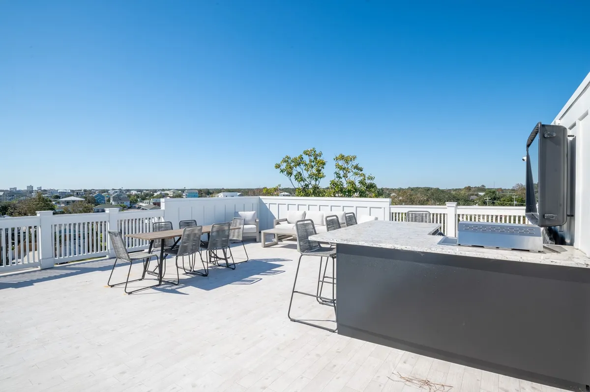 A vibrant rooftop scene with a barbecue grill, an outdoor dining table set for a meal, and stunning panoramic views stretching to the horizon. The ambiance suggests a lively yet comfortable environment ideal for group gatherings, evening cocktails, and taking in breathtaking sunsets.