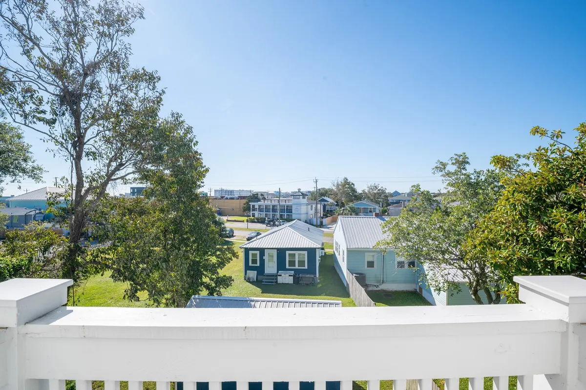 A view of blue houses, green trees, and an open sky creates a sense of community and relaxation. The image evokes a serene vacation mood, with visual cues that suggest opportunities for socializing and enjoying the scenic outdoor environment.
