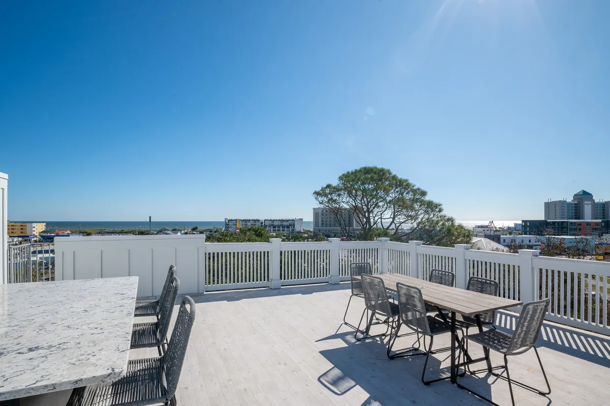 An outdoor dining and seating area overlooking the ocean, inviting guests to gather for meals, socializing, or relaxation with panoramic water views. The scene exudes a cheerful and relaxing vibe, perfect for sunset dinners or stargazing from the rooftop.