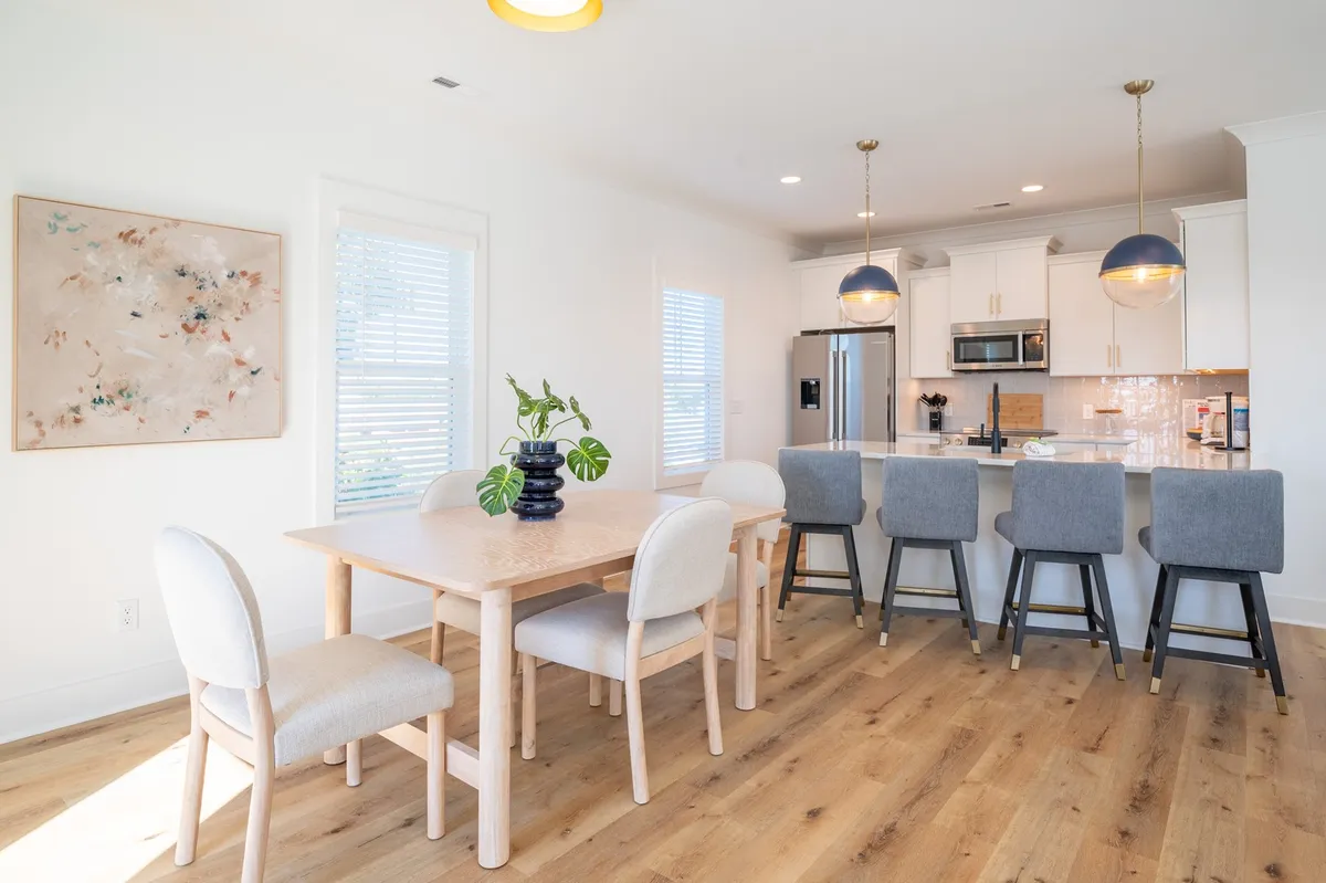 A contemporary dining area featuring a robust dining table, kitchen island, and modern artwork adorning the wall. The space is warm and perfect for both everyday meals and festive occasions.